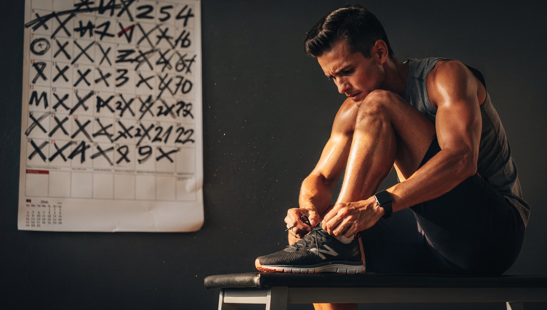 Homme déterminé qui lace ses chaussures à côté d'un calendrier mural rempli de croix, symbole d'une série de défis